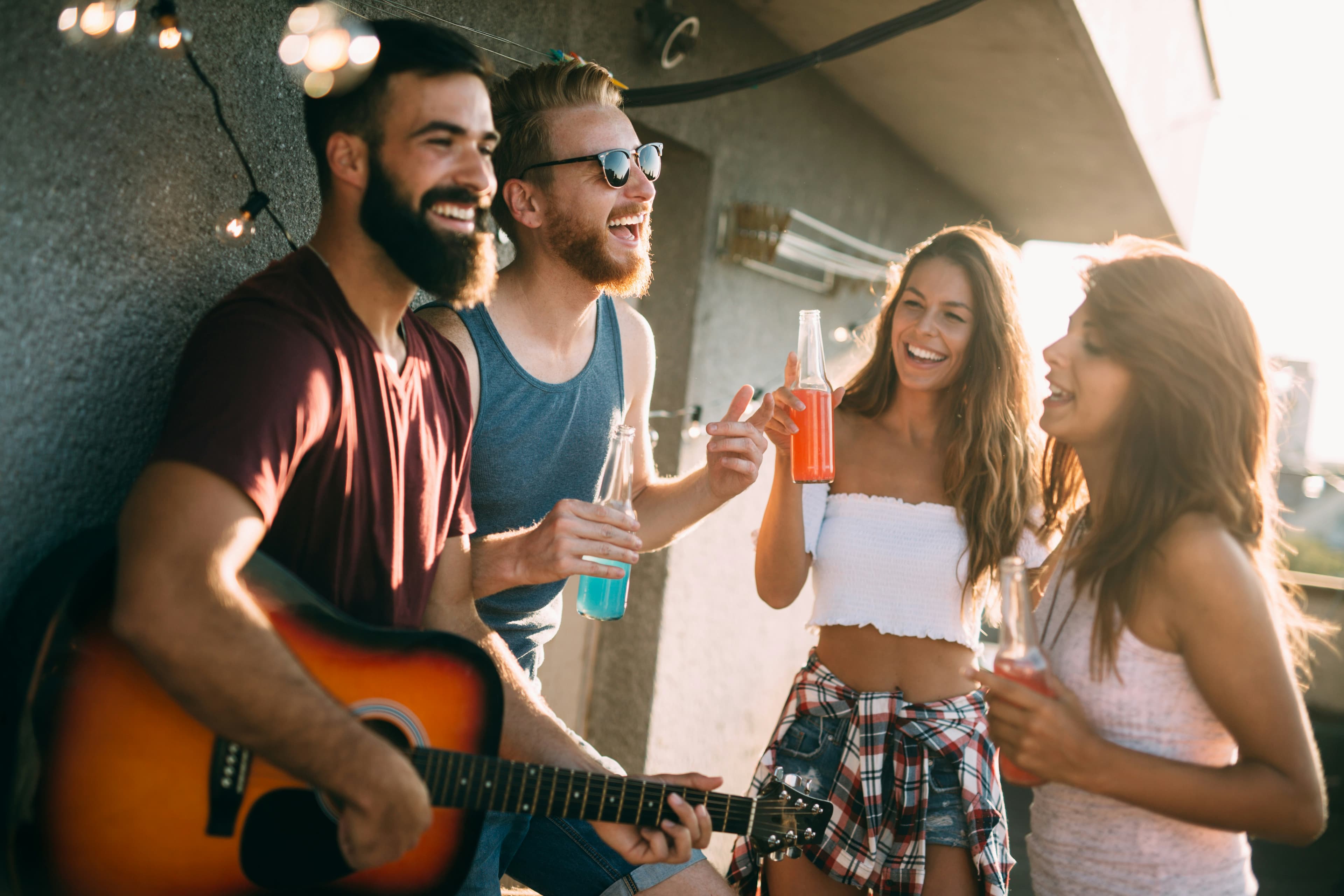 Four friends laughing together at a summer rooftop gathering